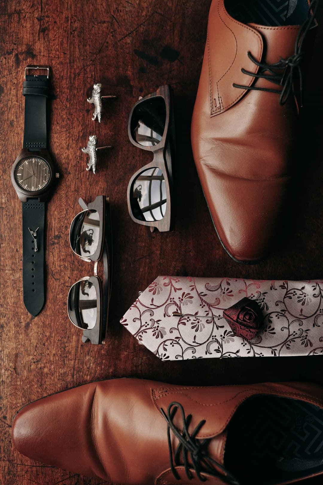 Men's accessories laid out including a watch, wallet, sunglasses, and leather belt